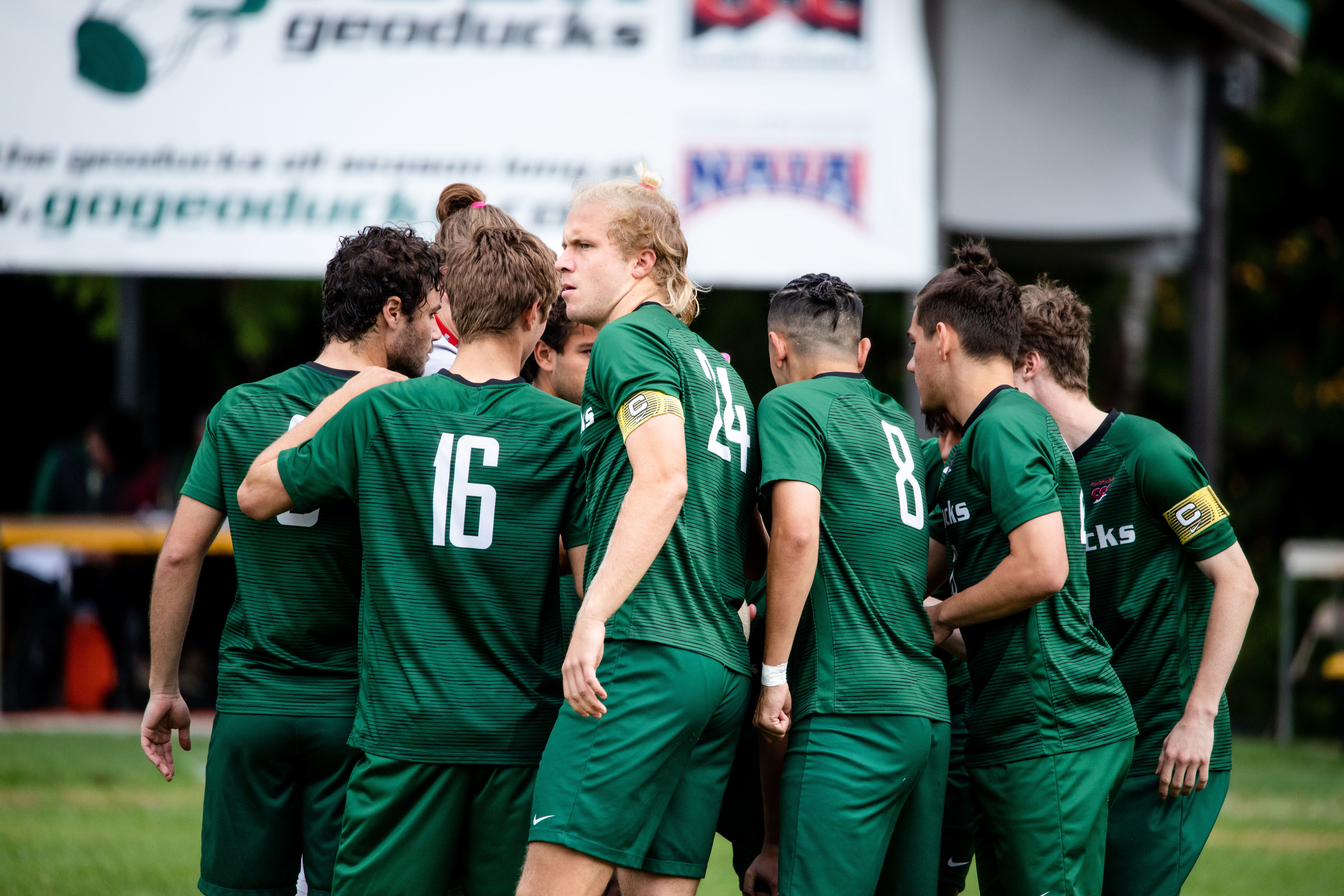 men's soccer players in green uniforms in a huddle