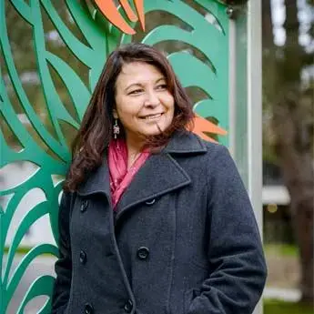 a photo of dawn lewis outside, wearing a black peacoat and looking to her left