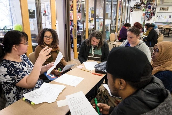 Group of six students seated at a table having a discussion