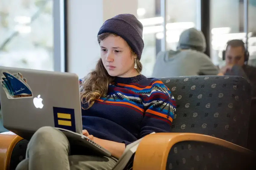 A student reads in the library while other students study in the background