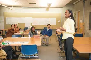 A woman stands in front of a classroom speaking