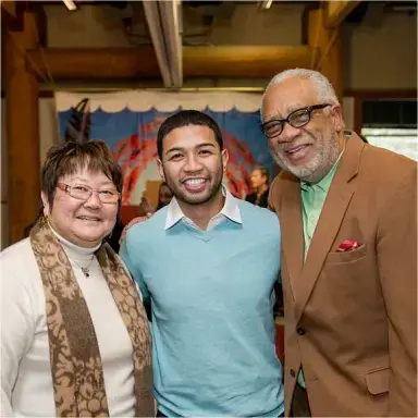 Three people standing together smiling and facing camera