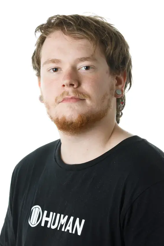 Person with redish hair and short beard wearing a Black t-shirt that says "Human"